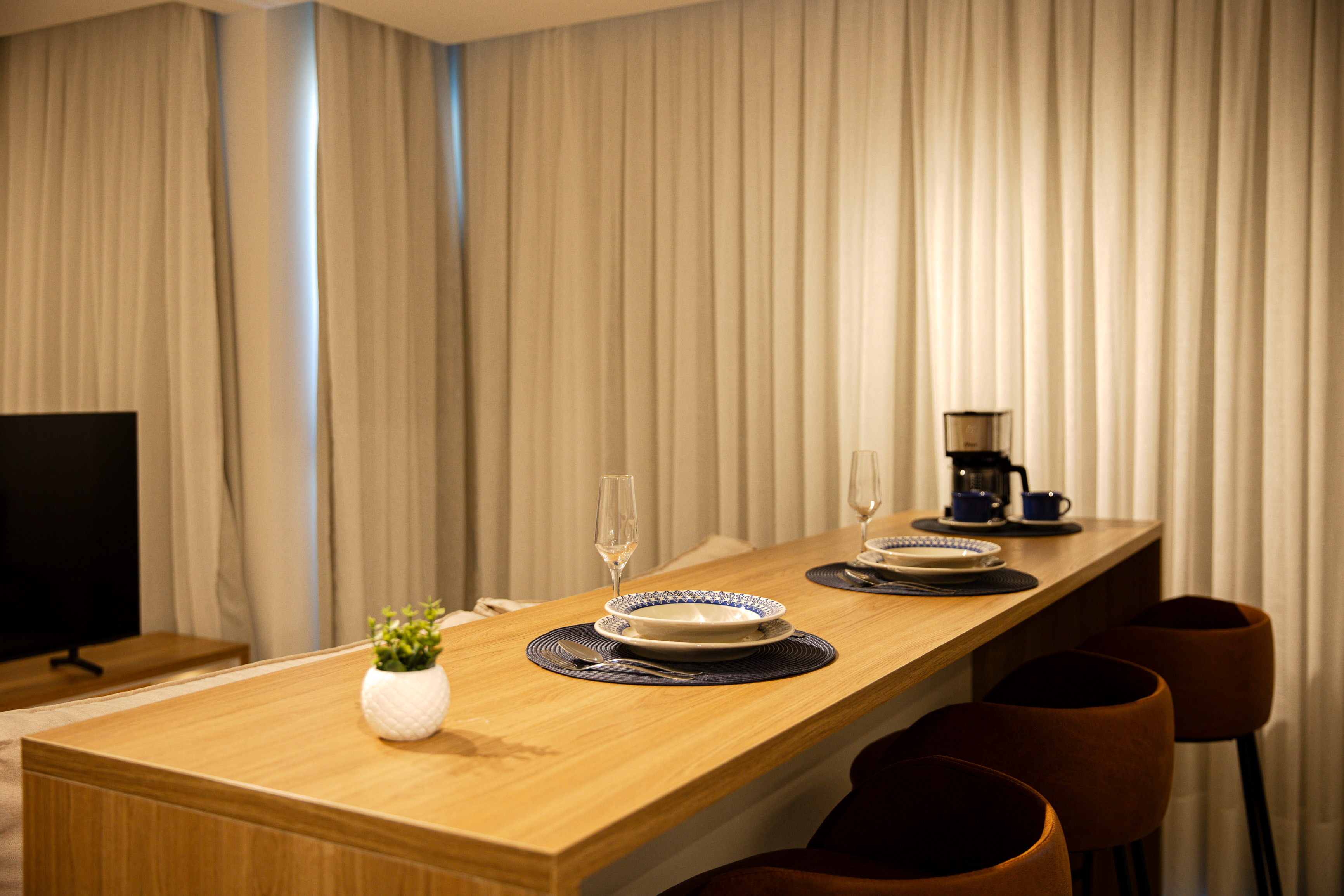 Bancada gourmet de refeições com banquetas e louças prontas para hóspedes Airbnb