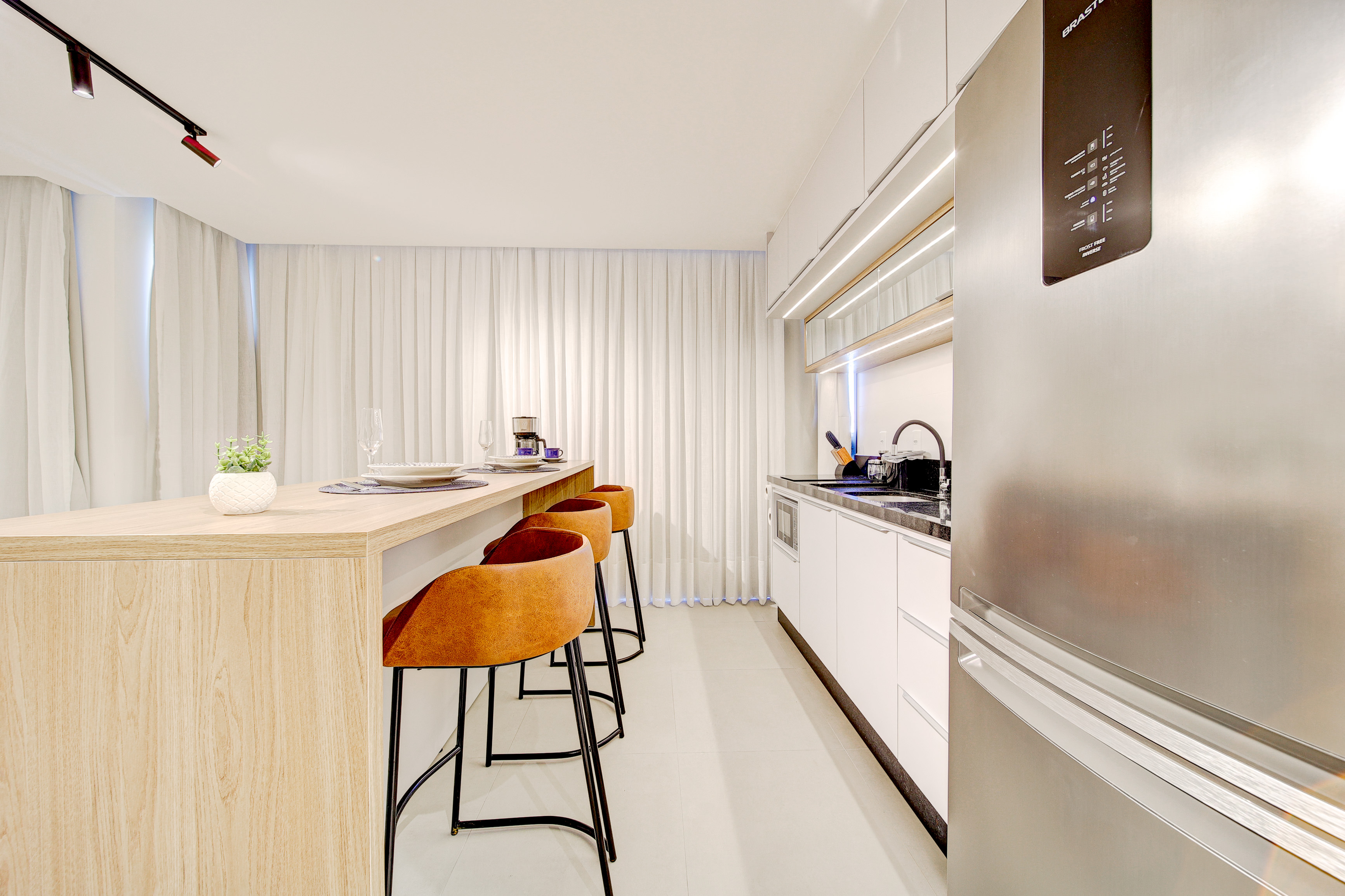 Cozinha planejada da unidade 103 com geladeira inox, bancada em granito e cooktop indução